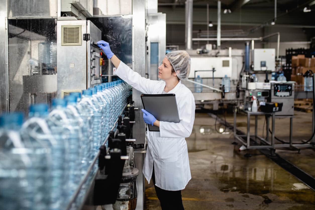 food and beverage plant worker checking bottling production line