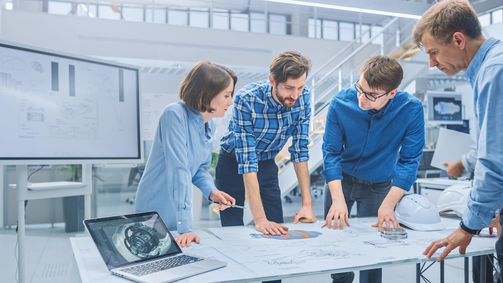 A group of peers working around a table discussing PLM and ERP